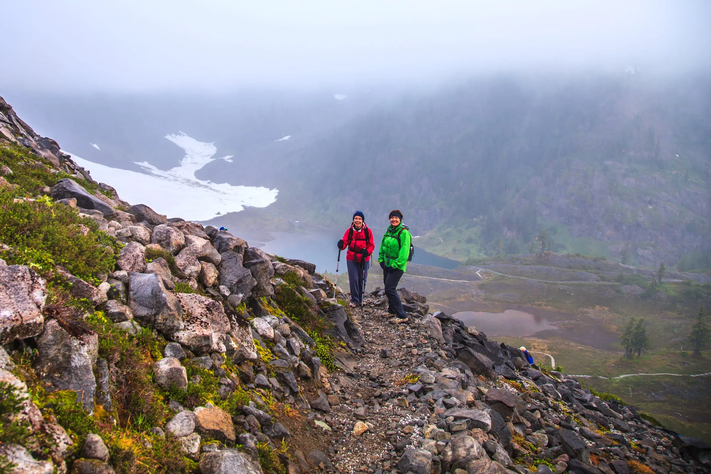 Hikers on a rocky trail above the Bagley Lakes basin at Mt. Baker Ski Area in autumn fog