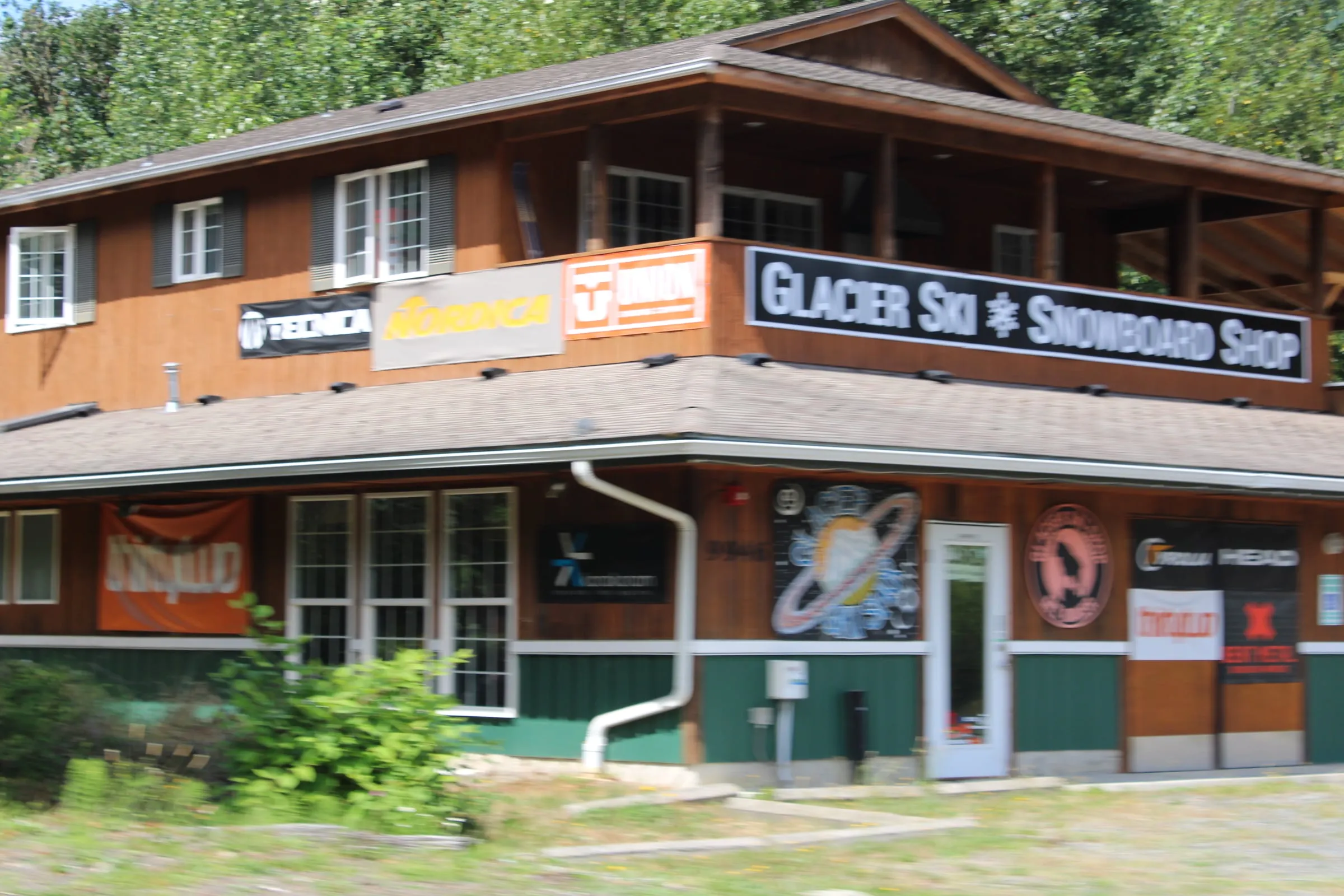 Wooden shop building on the Mt. Baker Highway in Glacier, Washington with a Glacier Ski and Snowboard Shop sign and ski brand banners